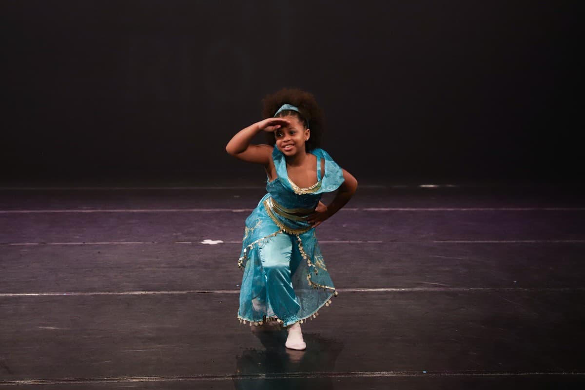 Aluna fantasiada de azul dançando no palco