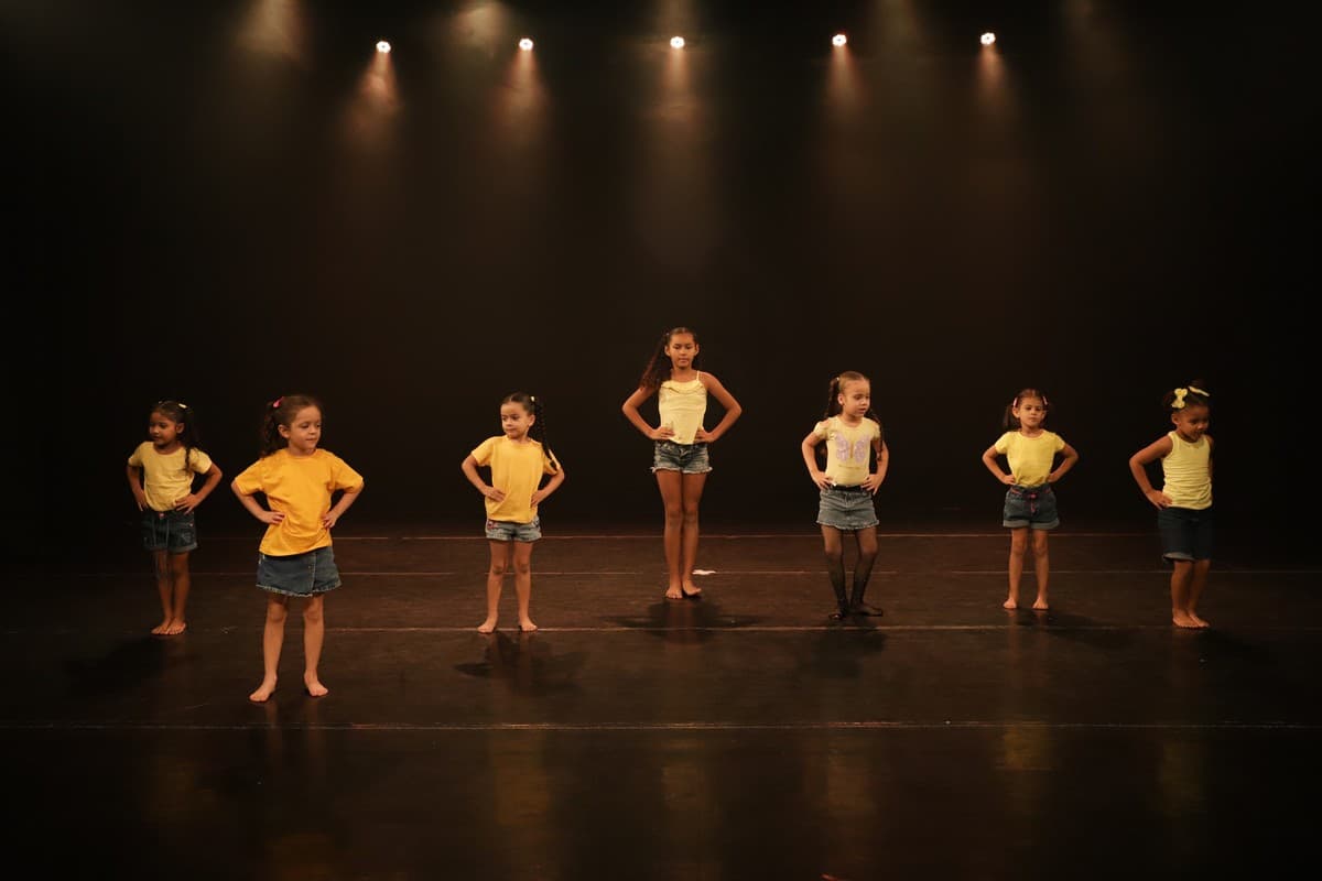 Turma infantil de camiseta amarela em fila no palco